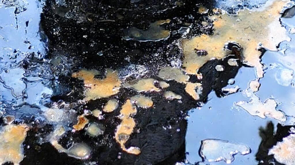 Close up of thick black engine oil sludge with contamination patches illustrating how ignoring engine oil facts and following myths can lead to deposits poor lubrication and engine damage