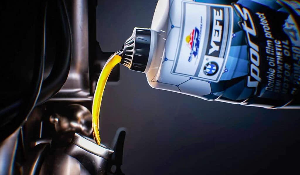 Golden high viscosity index synthetic engine oil pouring from Motul-style bottle into open engine oil filler neck, close-up macro shot demonstrating smooth low-temperature flow characteristics essential for rapid cold-start lubrication while maintaining film strength at operating temperatures, professional lubricant supplier VI technology showcase