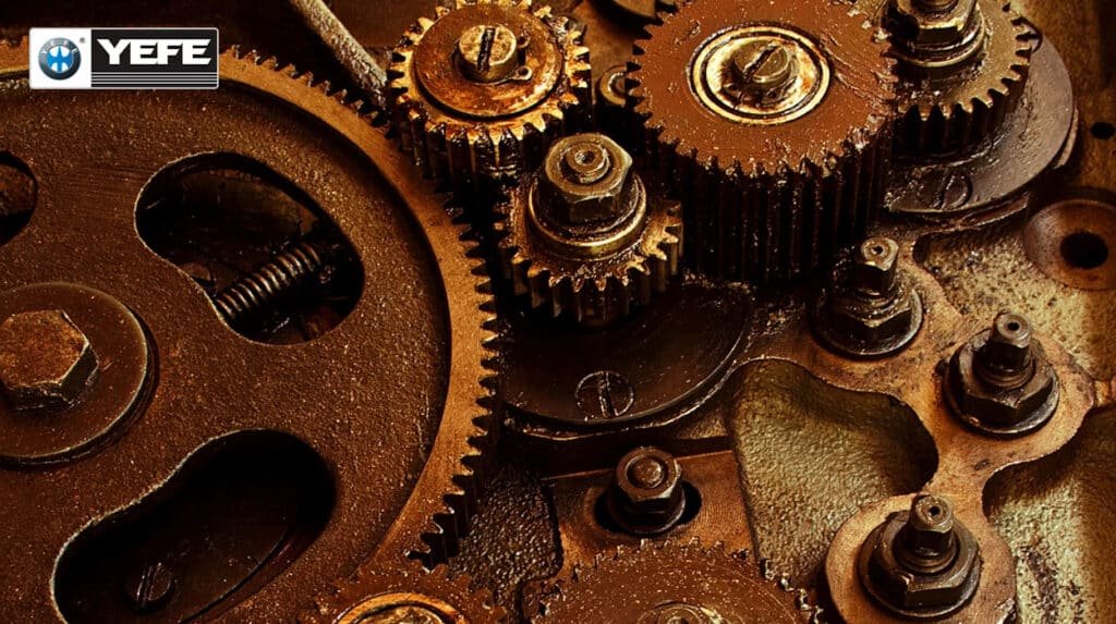 Rugged industrial gear train assembly with bolts and components, lubricated by YEFE SAE gear oil viscosity grades 75W-90 for excellent cold flow, 80W-90 for balanced performance, and 85W-140 for extreme high-temperature load protection.
