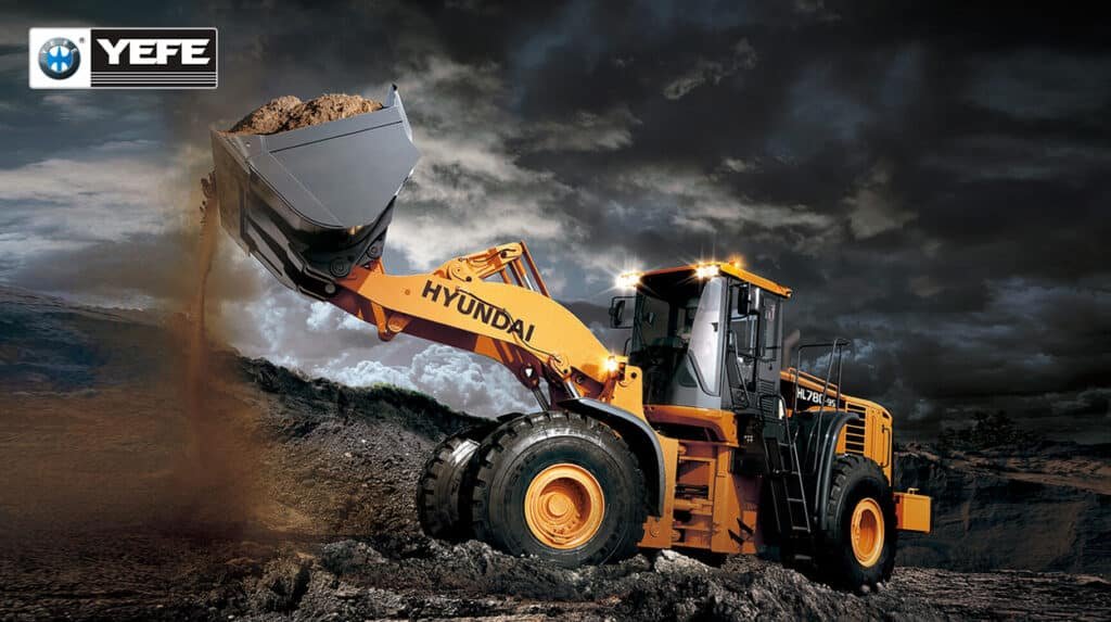 Yellow Hyundai wheel loader dumping soil in stormy conditions, highlighting hydraulic excavator arms and bucket requiring correct ISO VG hydraulic oil to avoid pump damage, overheating, and system failure from mismatched additives or low viscosity.