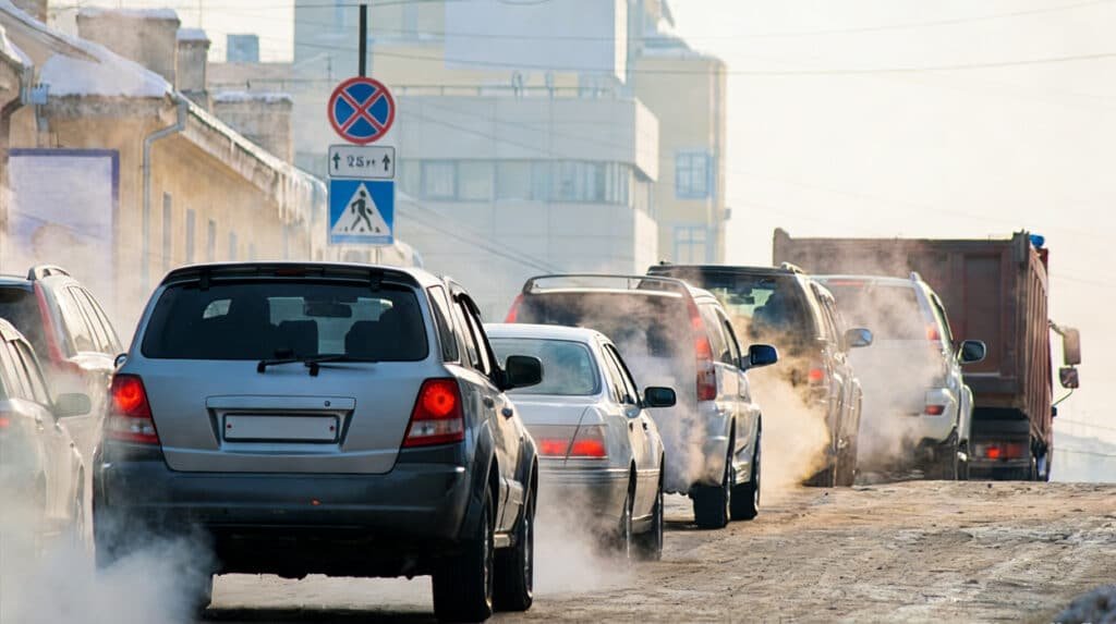 Cars emitting heavy exhaust smoke in winter traffic, illustrating potential symptoms of vehicle distress that can be caused by internal issues like using the wrong transmission oil leading to overheating and poor performance.