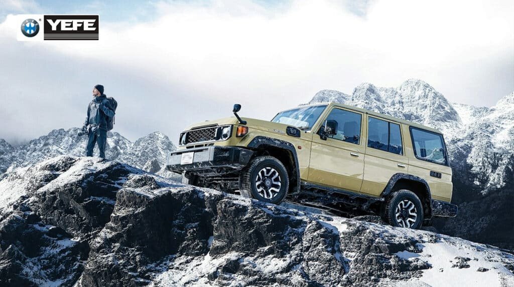 A beige Toyota Land Cruiser 70 Series off-road SUV navigating steep, rocky, snow-covered mountain terrain, with a hiker standing on a nearby ridge, visually demonstrating the vehicle's capability in extreme environments; the scene underscores the critical need for high-performance lubrication like YEFE's severe-duty diesel engine oil, which provides superior thermal stability, cold-start protection, and anti-wear performance essential for maintaining engine reliability and minimizing downtime in harsh, high-altitude, and off-road conditions.