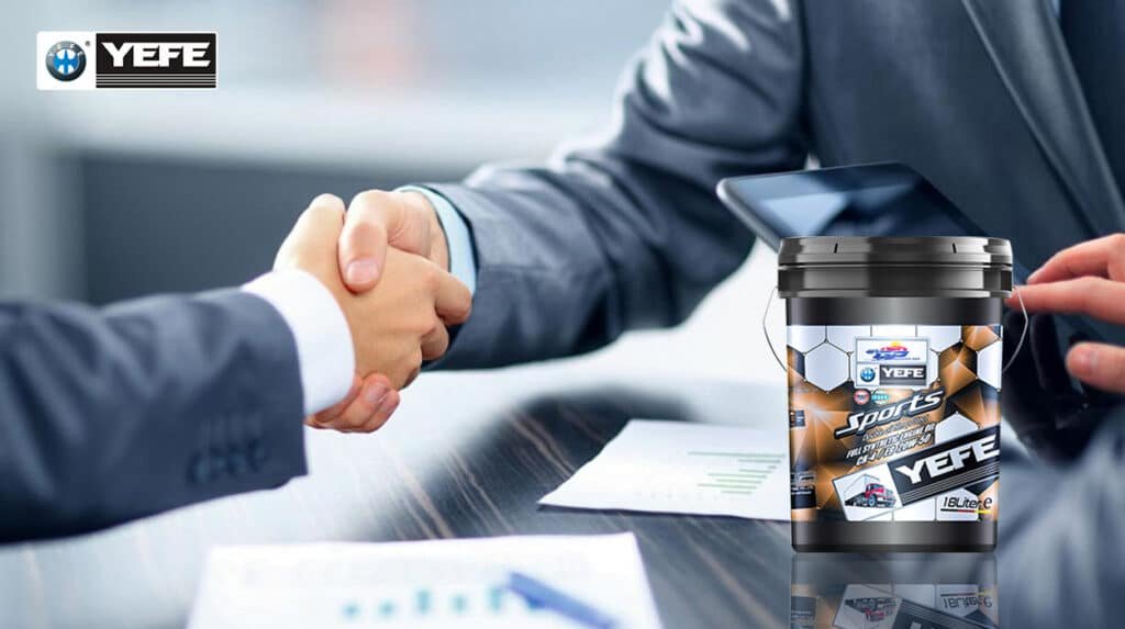 A 18-liter bucket of YEFE Sports full synthetic diesel engine oil (CH-4/E3 20W-50) placed on a business desk beside two professionals shaking hands, symbolizing trusted B2B partnerships and reliable lubricant supply for commercial fleet operators and industrial clients.