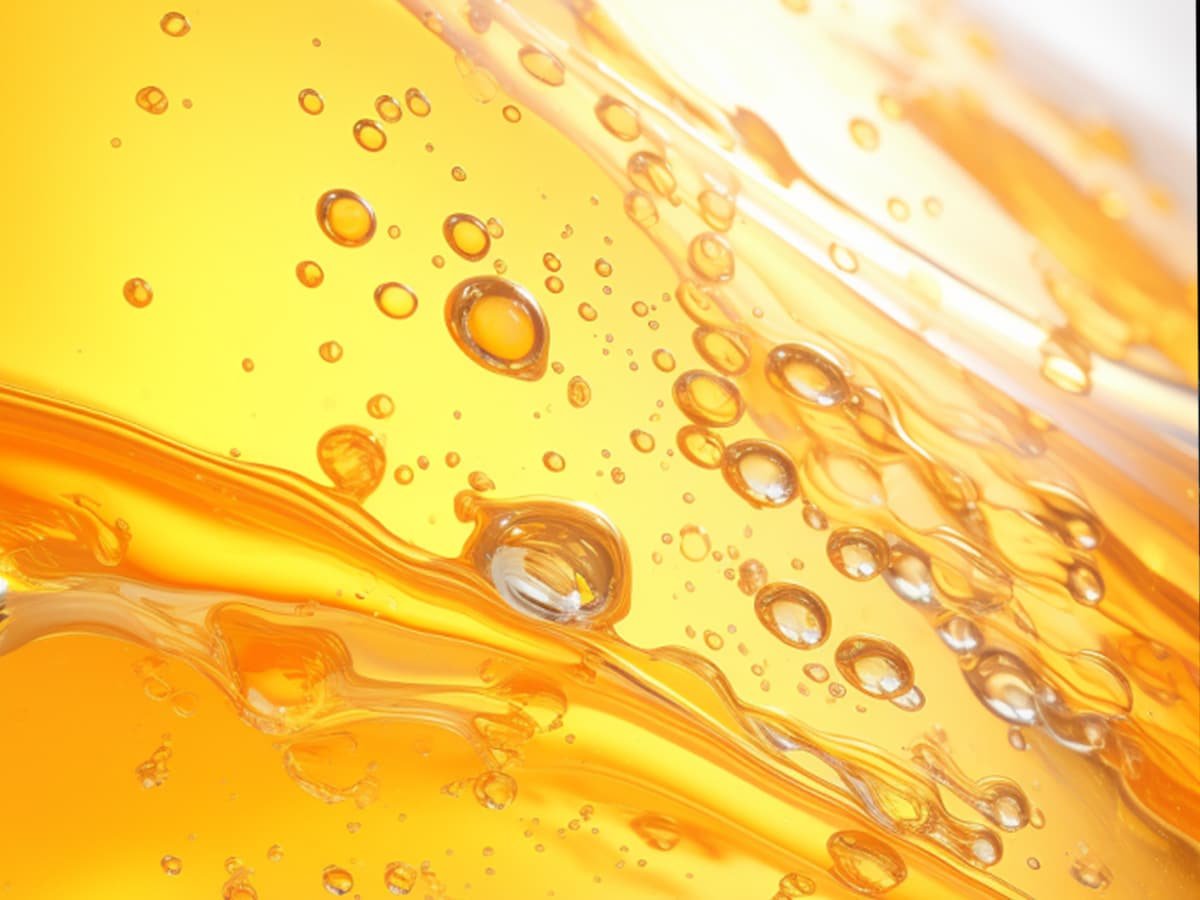 Close-up of golden lubricating oil with bubbles, representing advanced engine oil formulation for passenger vehicles